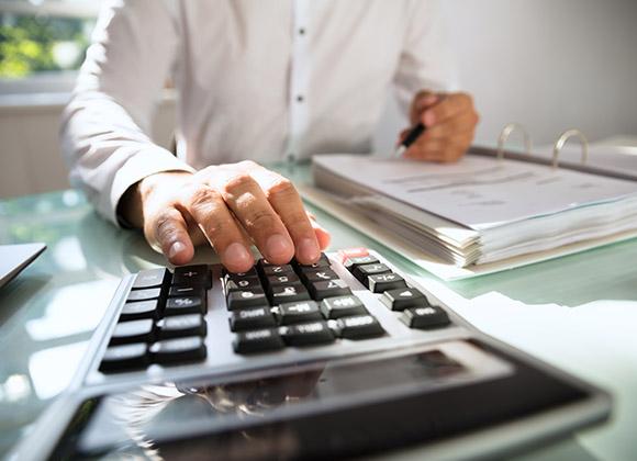 Man Working on Calculator for Accounting Services and Tax Preparation, in Duluth, GA